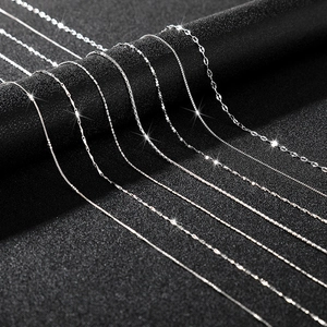 Detailed close-up of multiple silver chain styles including box and snake links on black fabric