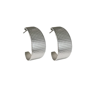 Close-up of silver C-shaped hoop earrings featuring a unique textured dotted surface