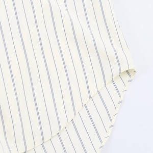 Macro view of a striped casual shirt hem featuring fine stitching and blue stripes