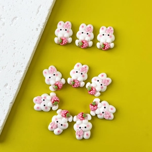 Flat lay of ten cute resin bunnies holding strawberries on a yellow background