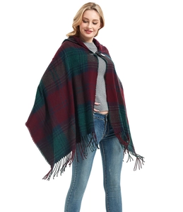 Detailed view of red and green plaid hooded poncho featuring soft tassel fringe trim