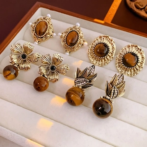 Vintage gold-tone flower earrings set with tiger eye stones and pearls on beige velvet
