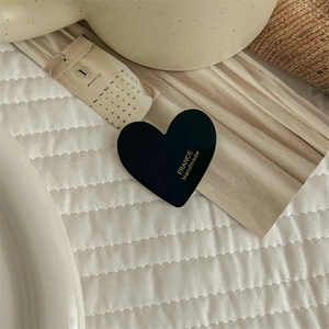Close-up of black acetate heart hair clip featuring France Handmade white text