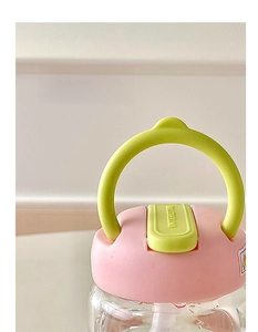 Detail of a portable glass bottle lid with pink plastic cap and green carrying handle