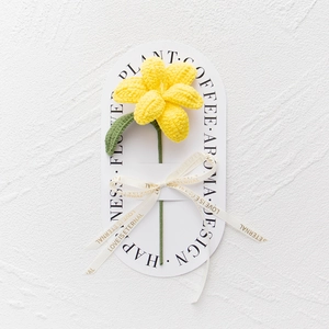 Nahaufnahme einer handgefertigten gelben Stricktulpe mit Love Is Eternal-Bandverzierung
