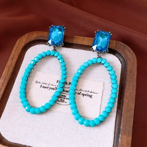 Macro detail of vintage style earrings featuring turquoise beads and blue crystal stones