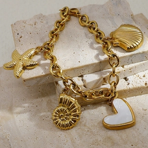 Detail of 18K gold plated bracelet with starfish, seashell, and heart charms on stone