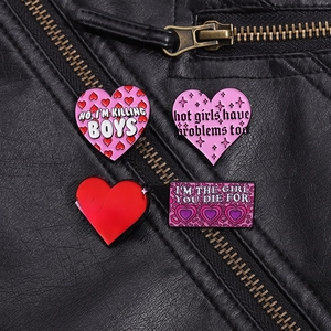 Detail of four pink punk heart enamel pins attached to a black leather biker jacket