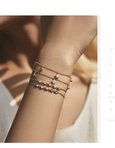 Detail of stacked s925 silver four-leaf clover and star bracelets in gold and silver
