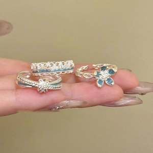 Detailed shot of silver flower rings with blue enamel and sparkling zircon accents