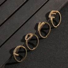 Detailed view of four-piece gold letter LOVE rings with rhinestones on a textured background