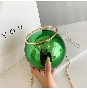 Dettaglio della borsa da sera a sfera in acrilico verde con manico e catena oro