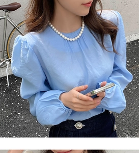 Vue détaillée d'un mannequin portant un chemisier bleu clair de style français en extérieur