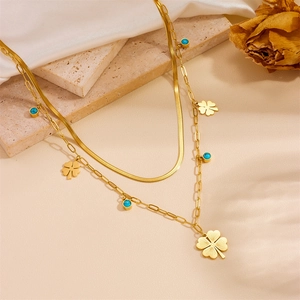 Detail of double-layer gold necklace with clover pendant and turquoise beads
