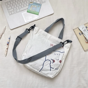 Detail of white canvas tote bag with cute cartoon prints and gray adjustable straps