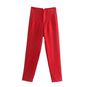 Detail of red high-waisted trousers featuring vertical pleats and slanted side pockets