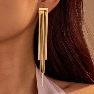 Elegant gold stainless steel tassel earrings with geometric zircon studs on a model