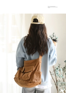 Brown canvas messenger bag detail showing multi-pocket structure on a female model