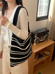 Close-up of minimalist black and white striped knit shoulder bag with soft woven texture