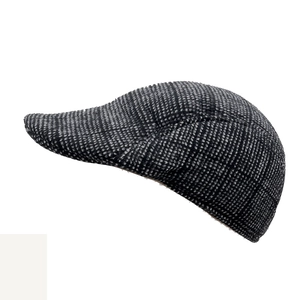 Close-up of the vintage black and white tweed texture on a wool-blend flat cap for men