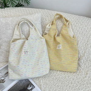 Detail of soft knit tote bags showing colorful textured fabric and woven brand label