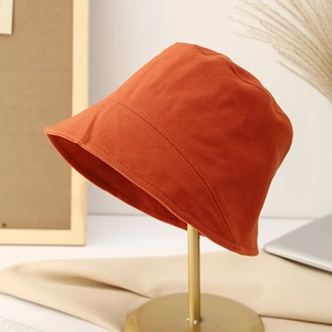 Close-up of caramel bucket hat on gold display stand with warm textured fabric detail