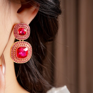 Detailed view of vintage gold earrings with red stones and pink crystals on model