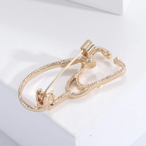 Detail view of the golden alloy stethoscope brooch with secure back pin closure