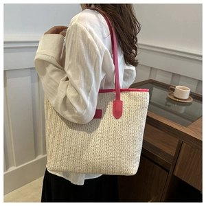 Detail of woven straw tote bag with fuchsia leather trim and herringbone texture