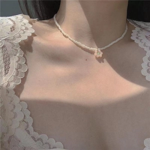 Close-up of beaded flower necklace with white pearls and pink resin pendant on neck