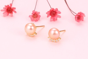 Macro shot of pink freshwater pearl earrings with zircon inlay on a soft pink background