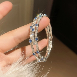 Close-up of triple-layer silver bangle with blue gemstones and sparkling zircon pavé