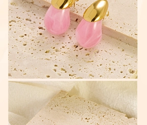 Detail of pink marble resin teardrop earrings with gold stainless steel studs on stone