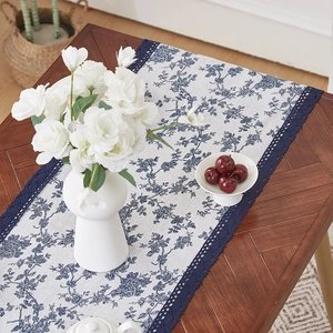 Blue floral cotton linen table runner with navy lace trim on a rustic wooden table