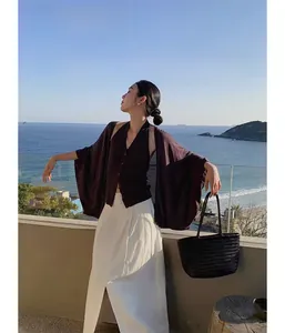 Detailed view of black woven cowhide leather tote bag held by a model on a balcony