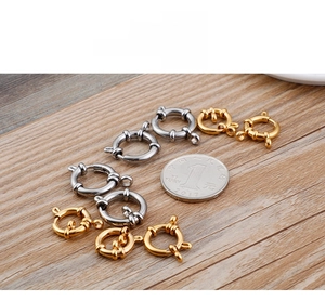 Detailed size comparison of gold and silver spring ring clasps next to a coin on wood