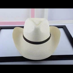 Detail of a beige straw cowboy hat featuring a brown leather band and metal buckle strap