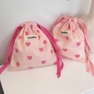 Detailed view of pink heart pattern drawstring canvas bags with woven brand label