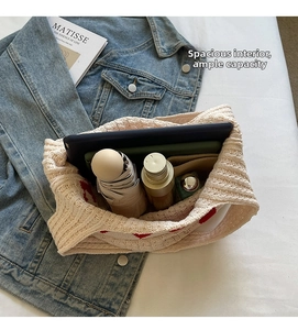 Detalle de gran capacidad de un bolso de punto con corazones que contiene tableta y paraguas