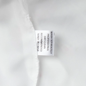 Detailed close-up of the washing care label and fabric texture on a white satin dress set