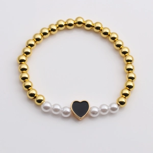 Golden beads and white pearls bracelet featuring a black heart charm on a white background