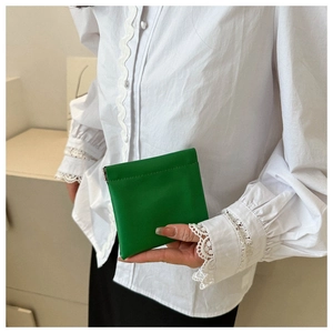 Close-up of a vibrant green mini leather pouch with flexible squeeze closure design