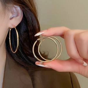 Macro detail of glossy gold hoop earrings showing the smooth metal finish and closure