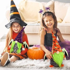 Detail of two girls holding spooky Halloween faceless gnomes with bat wings and star patterns