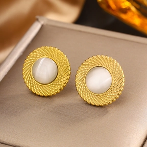 Détail de boucles d'oreilles vintage dorées avec pierre œil-de-chat sur boîte à bijoux