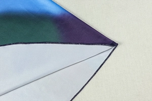 Détail du tissu dégradé bleu et vert montrant les coutures de précision et le textile fin