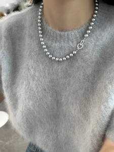 Detailed view of silver beaded necklace with zircon buckle on grey sweater