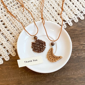 Detail of woven crescent and beaded heart necklaces on a vintage ceramic plate