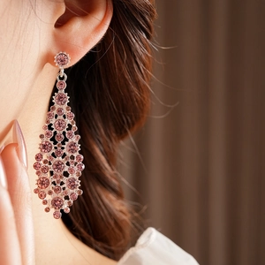 Detalle de pendientes largos con diamantes de imitación rosas en una modelo