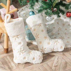 Close-up of white plush Christmas stockings with golden snowflake embroidery detail